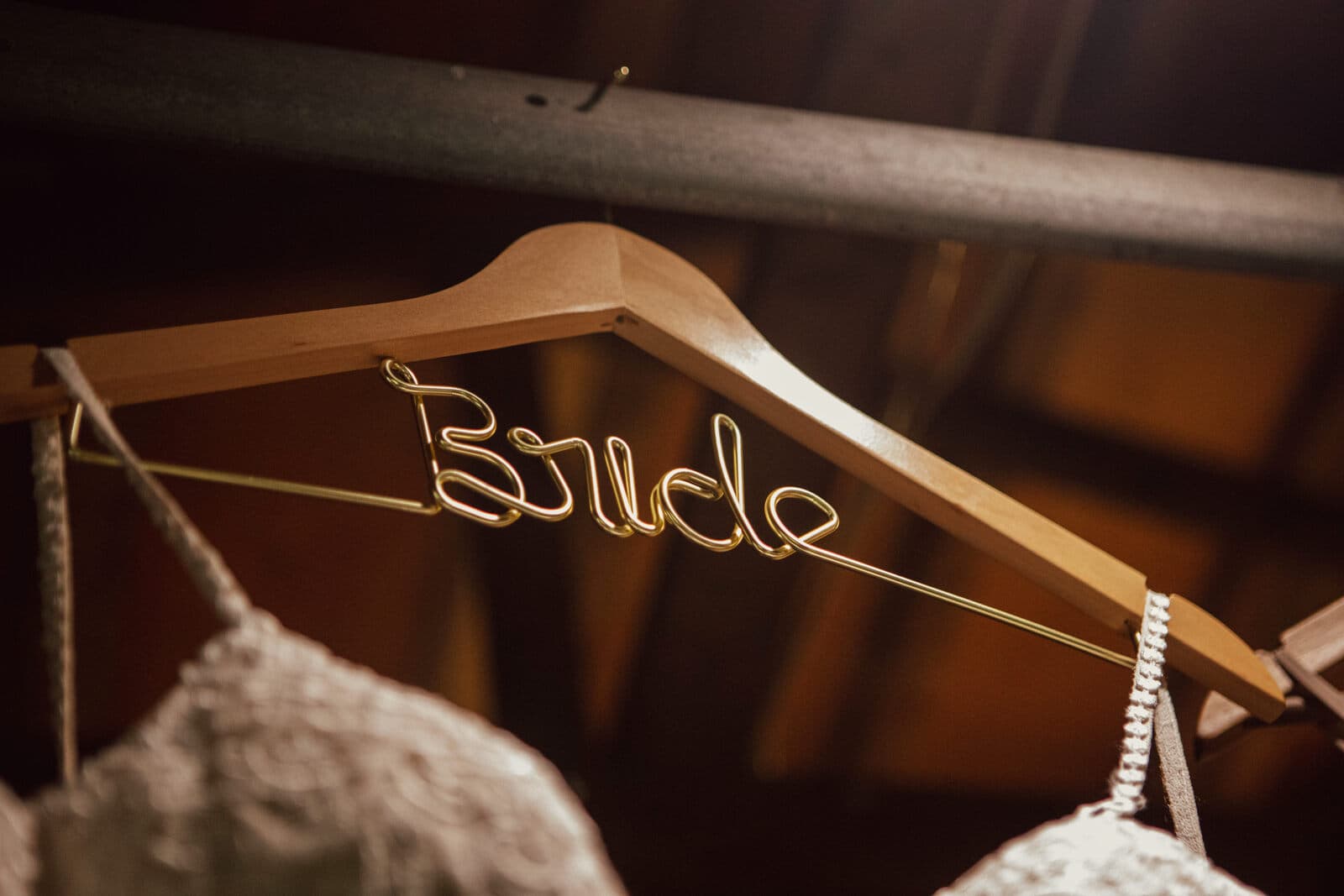 Personalized wire bride hanger holding a lace dress in the barn