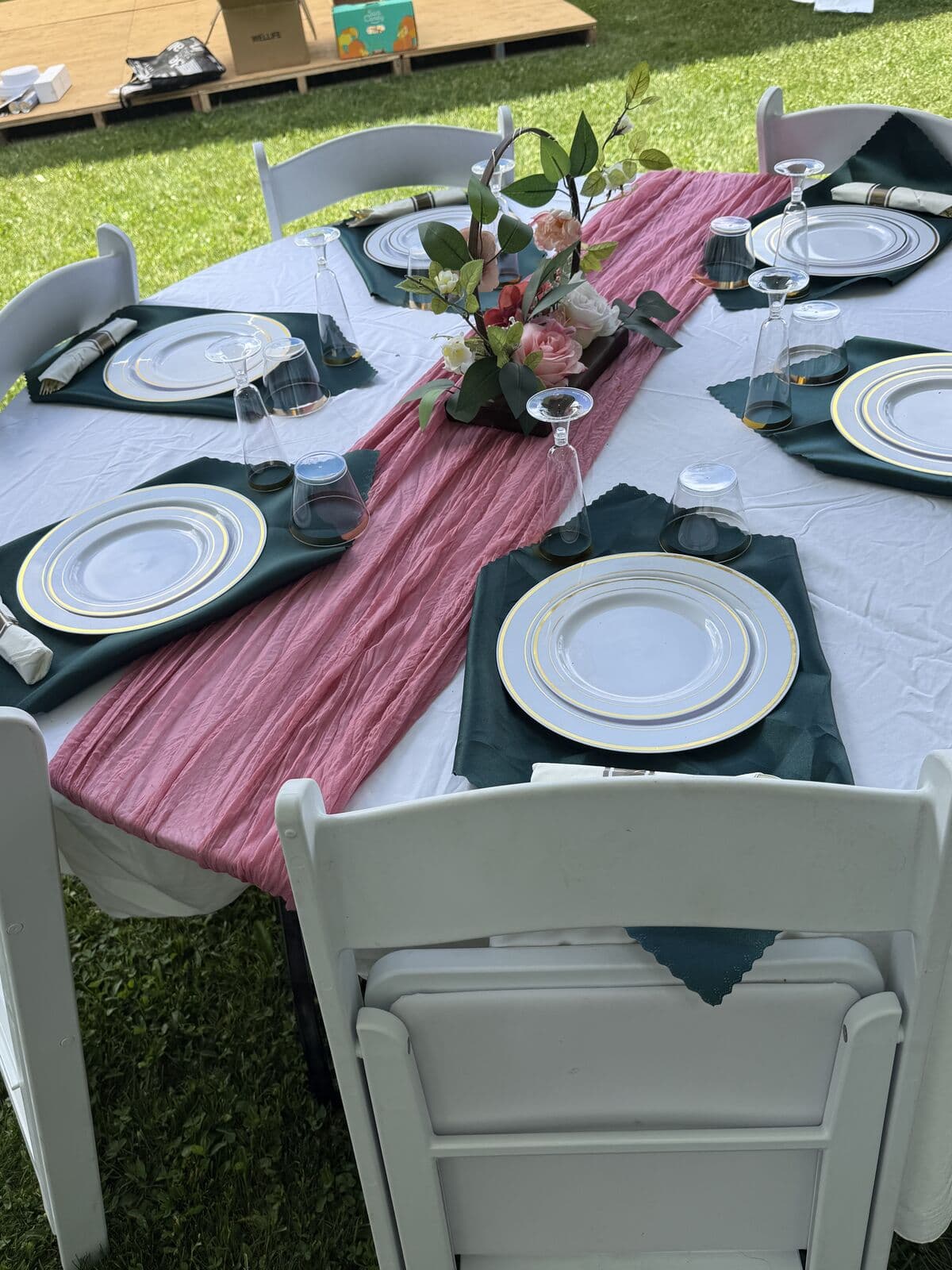 Place settings with rose runner, plates, and glassware on a round table