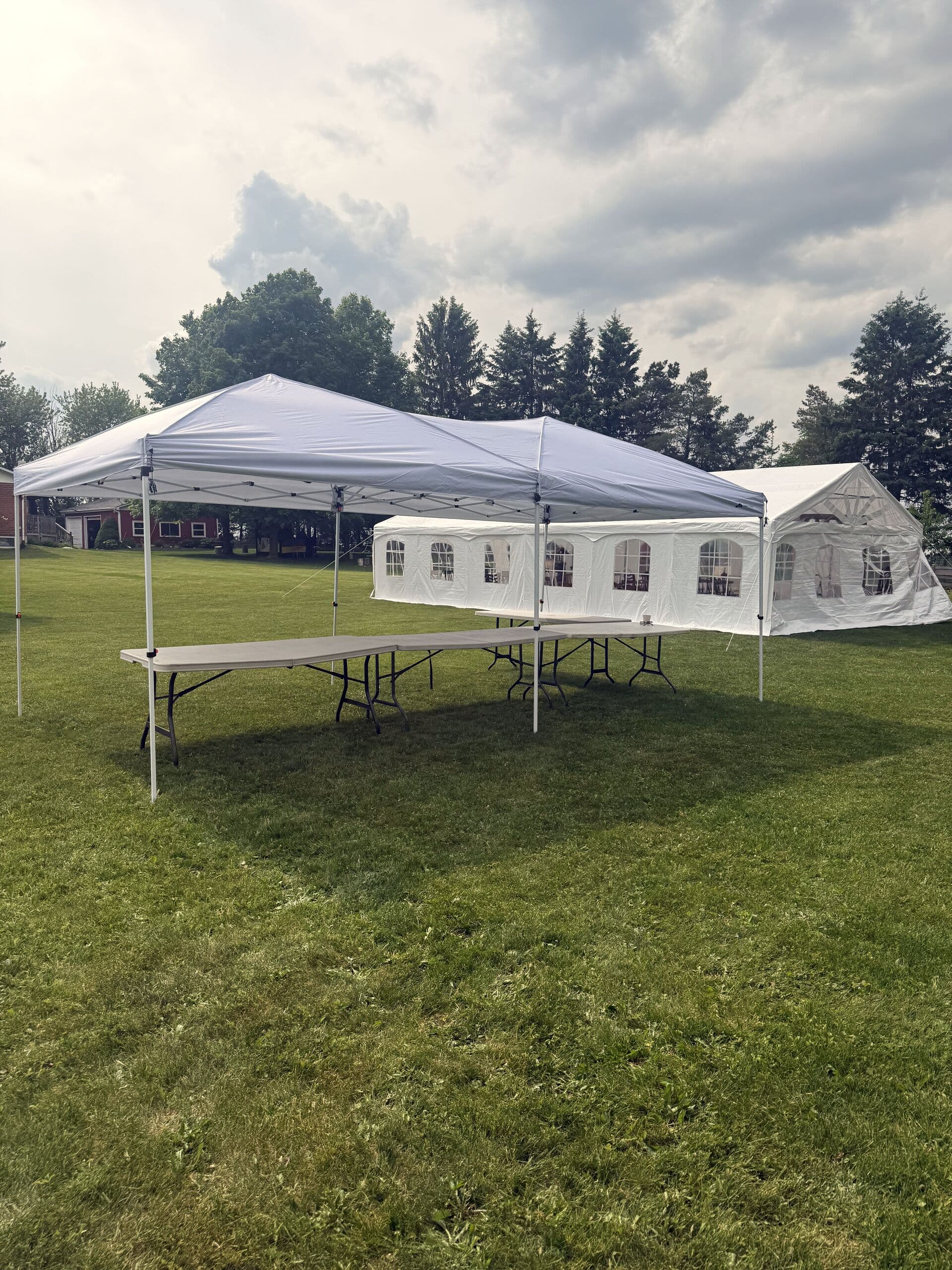 Open lawn with white event tents ready for an outdoor market at Rustic Hideaways